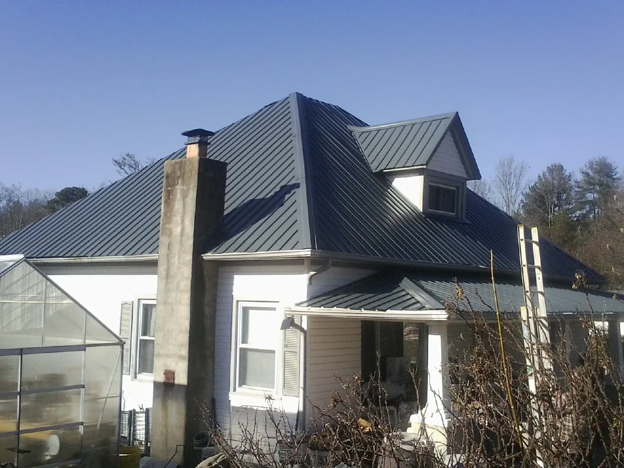 Dark blue standing seam metal roof on a white farmhouse with dormer — Slate & Tile Roof Repair by Roofing Brothers in Elmaton