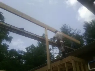 Carpenter setting a ridge beam over a new addition frame — Ice Dam Removal by Roofing Brothers in Elmaton