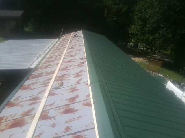 Old rusted panels beside newly installed green metal roofing — Wind Damage Roof Repair by Roofing Brothers in Elmaton