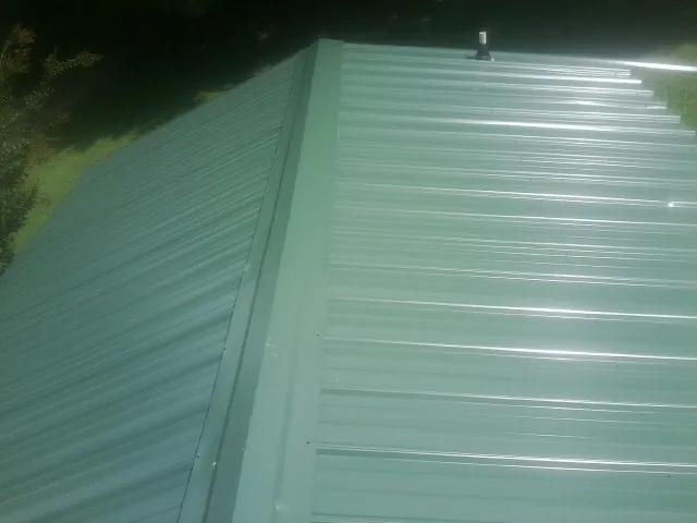 New green metal panels meeting at the ridge of a roof — Flat Roof Repair work by our crew in Elmaton