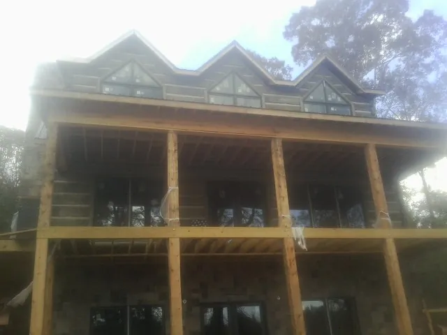 Dormers and porch framing on a large log home under construction — Roof Coating work by our crew in Elmaton