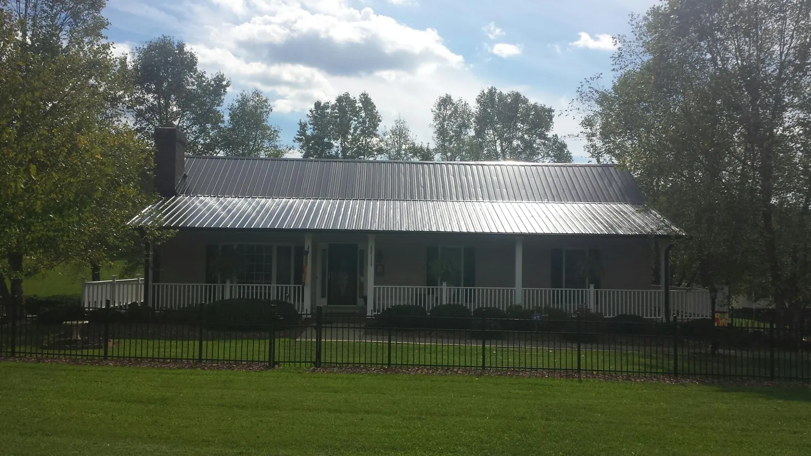Gray metal roof on a brick ranch with a full width front porch — Gutter Guard Installation work by our crew in Elmaton